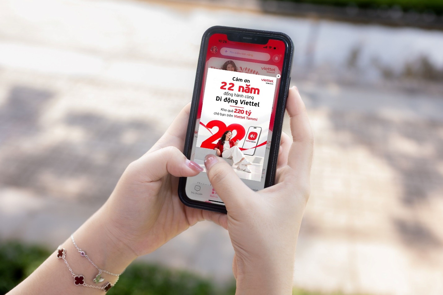 Hands holding a smartphone that displays the Viettel Tammi anniversary promotion