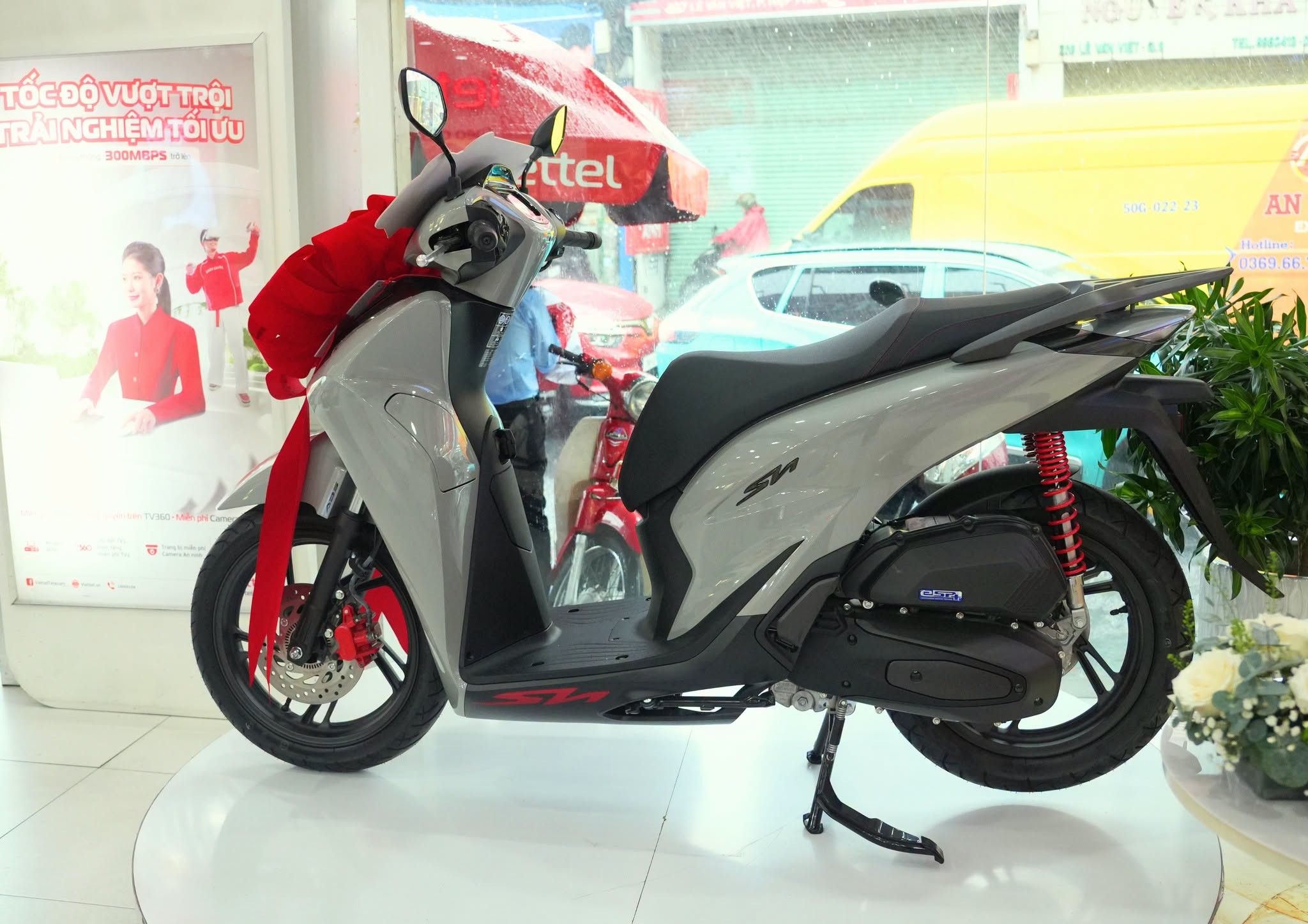A grey Honda SH125i Sport scooter with a red ribbon on display at a Viettel store