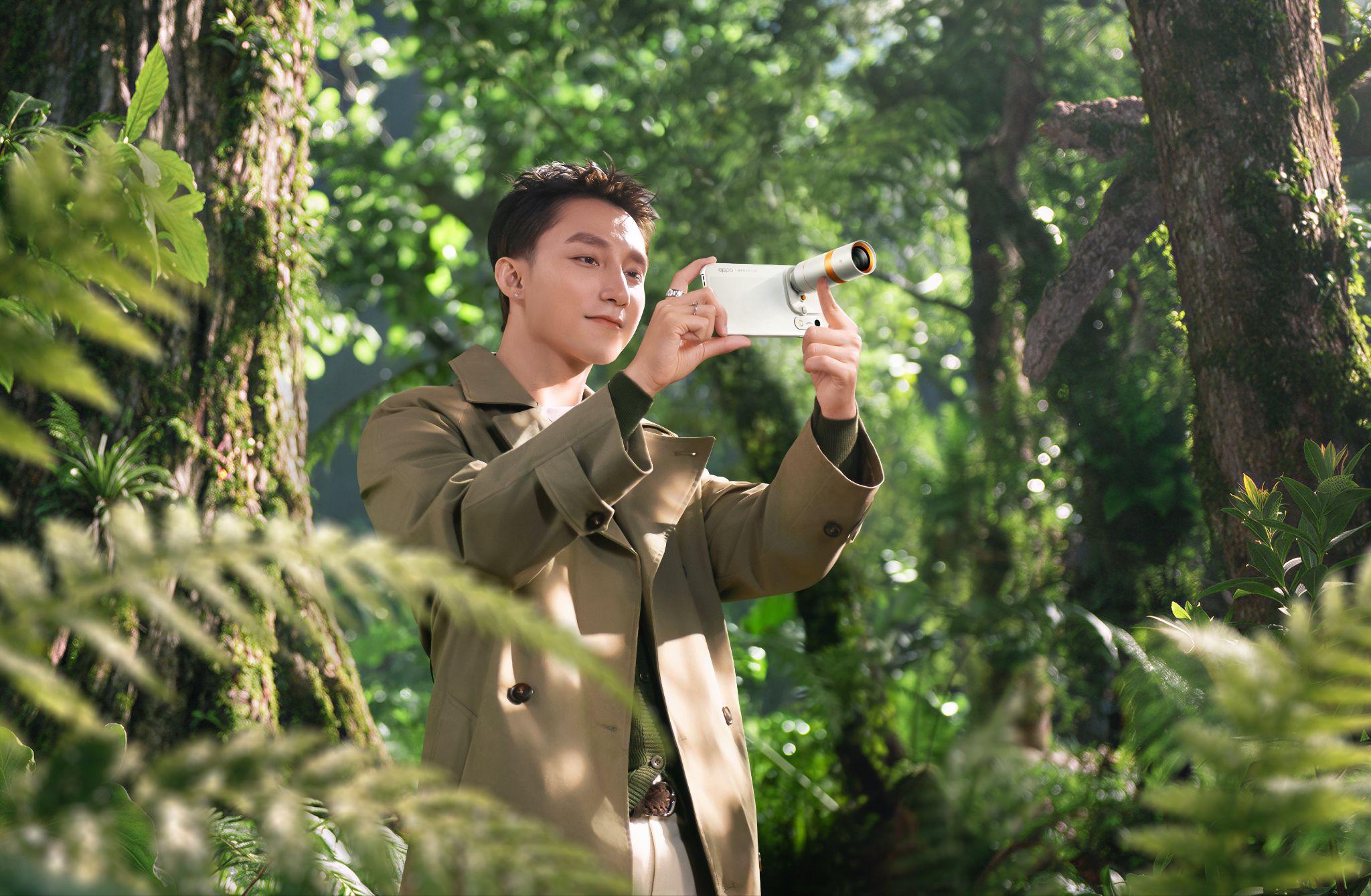 Sơn Tùng M-TP holding a white OPPO Find X10 fitted with a telephoto extender lens while standing in a green forest